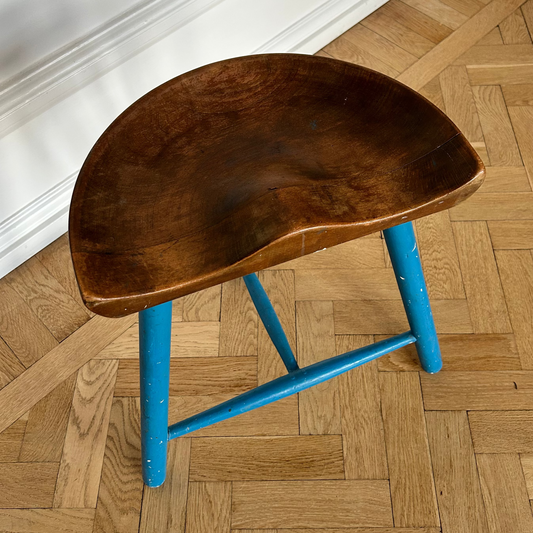 Wooden stool with a blue metal frame on a wooden floor.