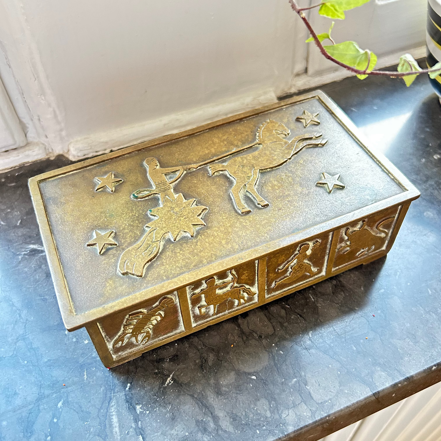 Decorative metal box with embossed designs on a marble surface