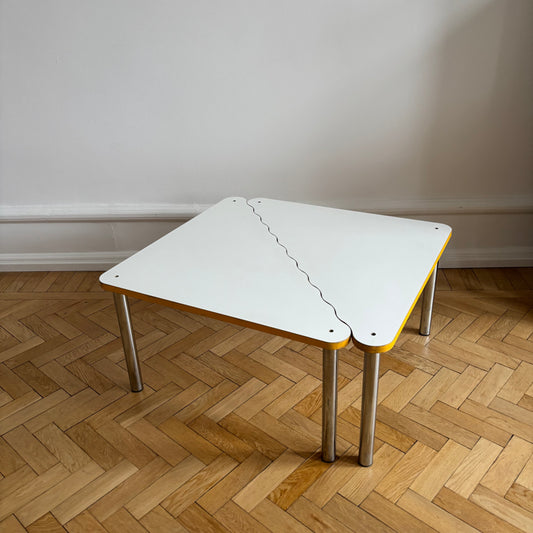 Modern Kukkapuro white and yellow table with metal legs on a wooden floor.