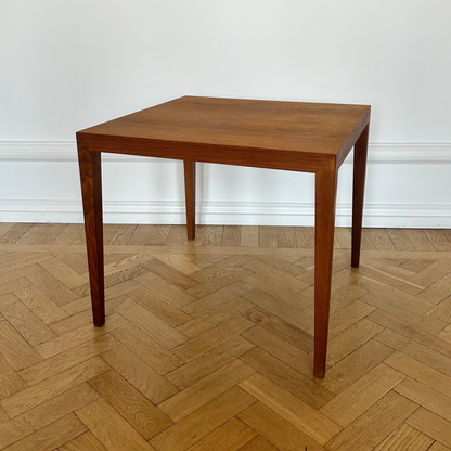 Wooden table on a herringbone wooden floor with a white wall background